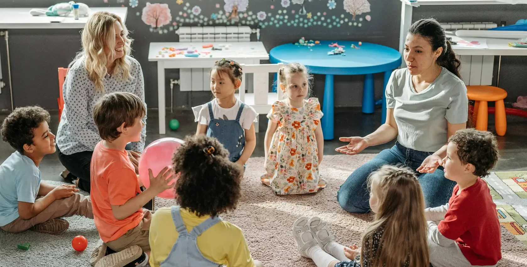 children in childcare circle timewith two female teachers